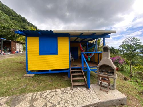 a small yellow and blue house with a ladder at Tamana Guadeloupe in Trois-Rivières