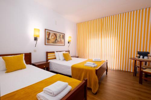 una camera d'albergo con due letti e un tavolo di Hotel Verde Pinho Bed&Breakfast a São Pedro de Muel