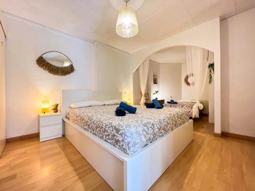a white bedroom with a large bed with blue pillows at Vivalidays Albert - Calella - in Calella
