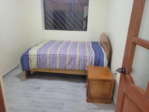 een slaapkamer met een bed en een houten tafel bij Apartamento cómodo y tranquilo. Garage gratuito in Cuzco