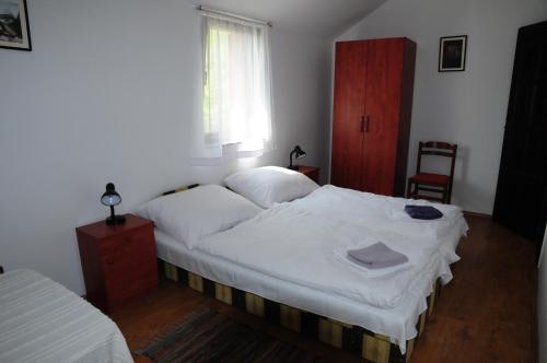 a bedroom with a bed with white sheets and a window at Beppe Vendégház in Abaliget