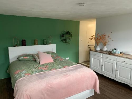 een slaapkamer met een bed en een groene muur bij Onze boerderij in Hoogersmilde