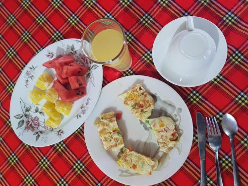 Zion Care Homestay في أروشا: طاولة مع طبقين من الطعام وكأس من عصير البرتقال