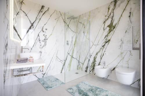 baño con pared de mármol, lavabo y aseo en crabonaxa suites, en Villasimius