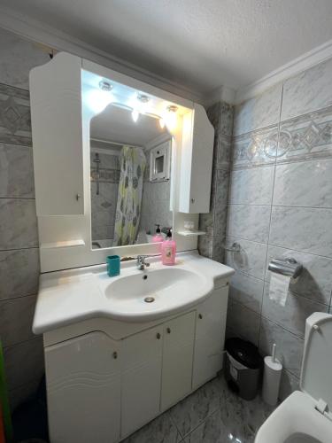 een badkamer met een witte wastafel en een spiegel bij Sofi’s Apartment in Kavala