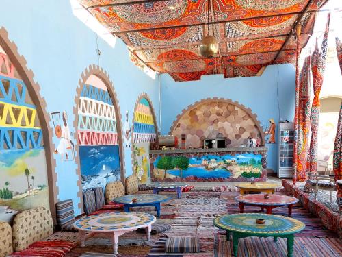 une chambre avec des tables et des peintures sur les murs dans l'établissement Hllol Hotel Abu Simbel, à Abou Simbel