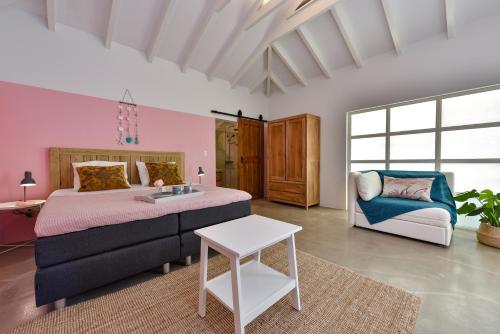 a bedroom with a bed and a couch and a table at Koeriboeri Aruba Lodges in Babijn