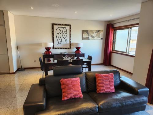 a living room with a leather couch and a table at Magnífico Apartamento T2 Praia de Esmoriz in Esmoriz