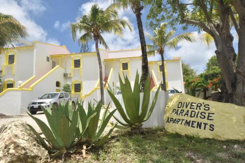 a yellow and white house with palm trees and a sign at Diver's Paradise Bonaire in Kralendijk