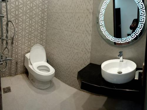 a bathroom with a toilet and a sink and a mirror at Haven Lodge - 7BR Luxury Vacation Home with Mountain View in Islamabad