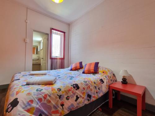 a bedroom with a bed and a red table at Meraki Hostel - Cerro Alegre - Valparaíso in Valparaíso
