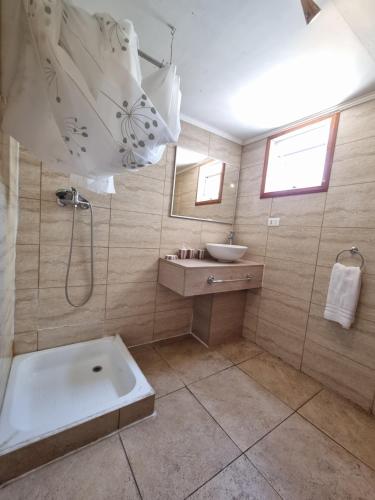 a bathroom with a shower and a sink and a tub at Meraki Hostel - Cerro Alegre - Valparaíso in Valparaíso