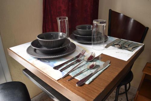 a wooden table with plates and utensils on it at MYRTOS ROOMS in Paralia Katerinis