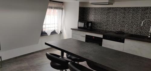 a kitchen with a table with chairs and a microwave at Le Bronze, appartement de standing en hypercentre in Sarreguemines