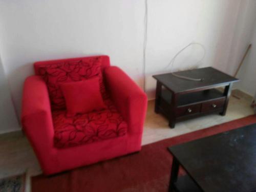 - Silla roja en la sala de estar con mesa en شاليه بقرية كورنادو السخنه, en Ain Sokhna