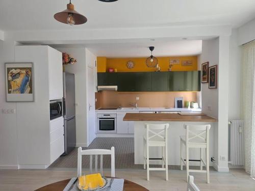 une cuisine avec des armoires blanches et vertes et des tabourets de bar dans l'établissement Le Loft Blainville, à Dieppe