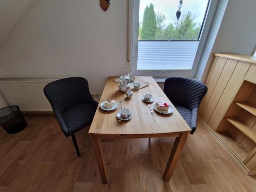 een houten tafel met twee stoelen en borden erop bij Ferienwohnung Renken in Upgant-Schott
