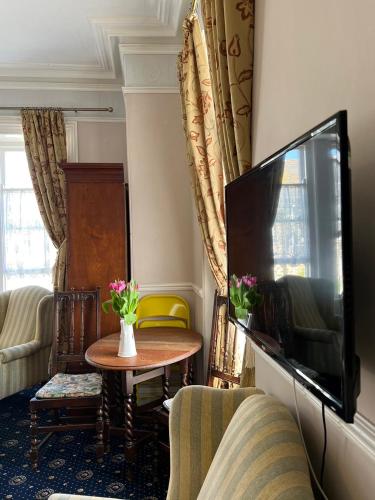 a living room with a flat screen tv and a table at Penzance Seaside studios in Penzance