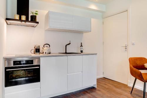 a kitchen with white cabinets and a stove at Haarlem Hotel Suites in Haarlem