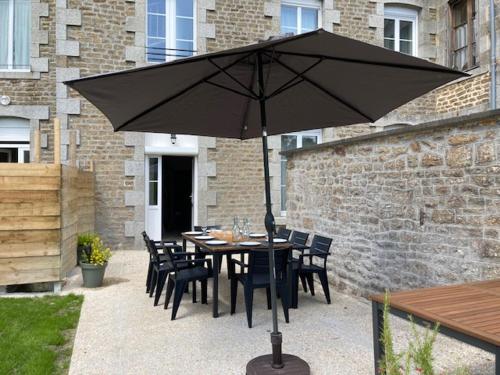 a table with chairs and an umbrella on a patio at Gîte de la Poste in Saint-Fraimbault