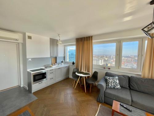 a living room with a couch and a kitchen with windows at ComeWa Apartments in Warsaw