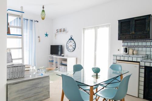 Ficus Traditional Apartments في كيفالوس: مطبخ مع طاولة زجاجية وكراسي زرقاء