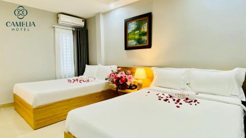 two beds in a hotel room with flowers on them at Camelia 108 Le Lai Hotel in Ho Chi Minh City