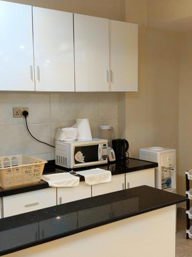 a kitchen with white cabinets and a microwave on a counter at Kaisa gardens in Nairobi