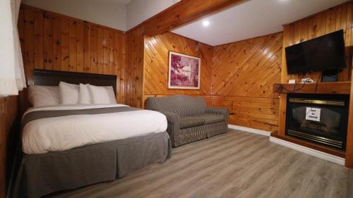 een slaapkamer met een bed en een stoel en een open haard bij Algonquin Lakeside Inn in Dwight