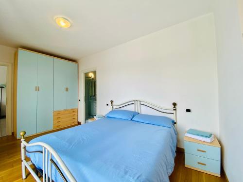 a bedroom with a large bed with blue sheets and a cabinet at A dream on the lake in Ranco