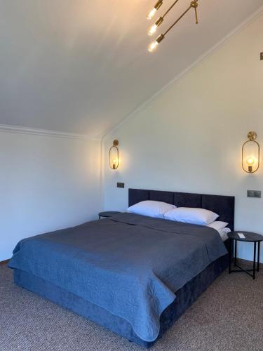 a bedroom with a large bed with a blue blanket at Райский Дворик in Pogreby