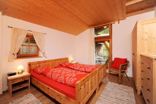 ein Schlafzimmer mit einem roten Bett in einem Zimmer in der Unterkunft Botenhof - Urlaub auf dem Bauernhof - Agriturismo in Sarntal