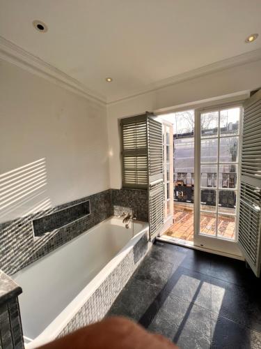 y baño con bañera y ventana. en Knightsbridge villa, Westminster, en Londres