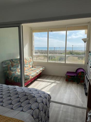 - une chambre avec un lit, un canapé et des fenêtres dans l'établissement Appartement vue exeptionnelle sur la mer 6 personnes, au Barcarès