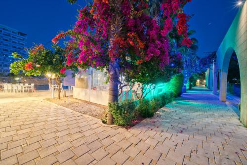 a tree with pink flowers on a sidewalk at Luxury Two Bedroom Penthouse in Caesar Resort & SPA, Long Beach in Perivolia tou Trikomou