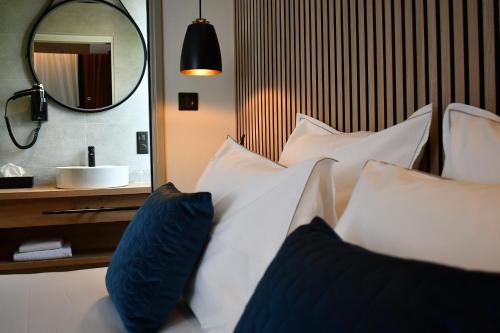 1 cama con almohadas azules y blancas y espejo en Le Cheval Blanc - Lac du Der - Logis Hotel, en Giffaumont-Champaubert