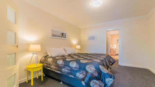 a bedroom with a bed and a yellow table at 1-83 Thompson Avenue, Cowes in Cowes