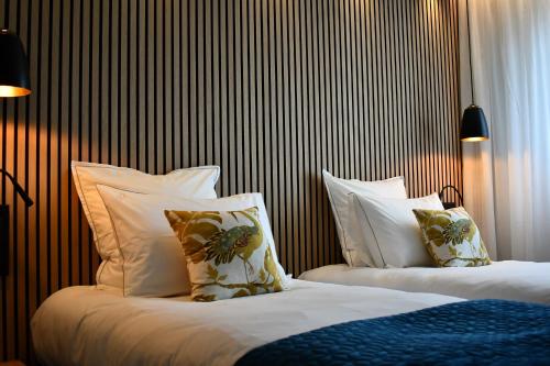 a bedroom with two beds with white pillows at Le Cheval Blanc - Lac du Der - Logis Hotel in Giffaumont-Champaubert