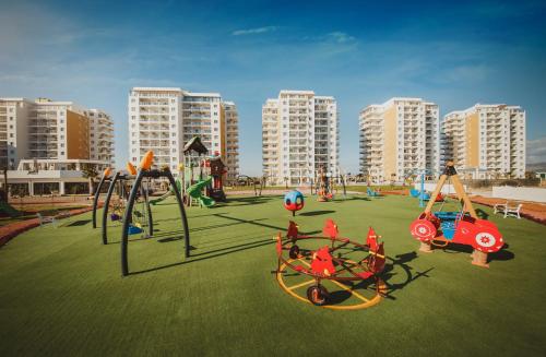 a playground with play equipment on a grass field at Luxury Two Bedroom Penthouse in Caesar Resort & SPA, Long Beach in Perivolia tou Trikomou
