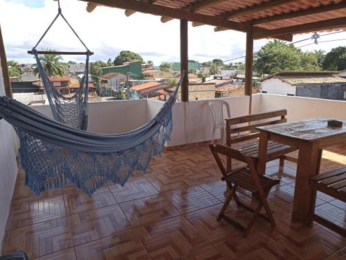 a hammock on the roof of a house with a table and chairs at Aluguel de suites e Apartamento in Itacaré