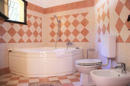 uma casa de banho com uma banheira, um WC e um lavatório. em Quiet villa with swimming pool near Monaco em Peille