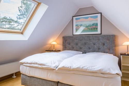 a attic bedroom with a bed and two windows at Strandleben 11 - Hans Kinder in Ahrenshoop