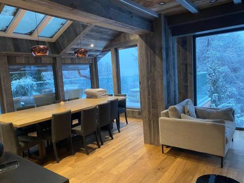 une salle à manger avec une table, des chaises et des fenêtres dans l'établissement Masara - 5-room chalet plus sauna and jacuzzi 12 p, à Peisey-Nancroix