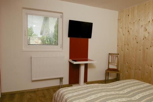 a bedroom with a bed and a television on the wall at Pension Archa Mikulov in Mikulov