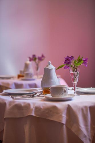a table with plates and a tea pot and flowers on it at Aetoma Hotel in Nafplio