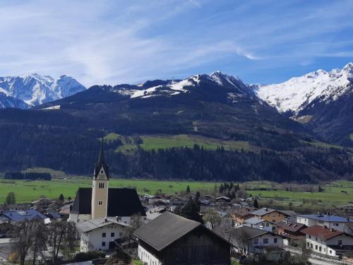 a small town with a church and snow covered mountains at Piesendorf Pad - Oberbichl in Piesendorf