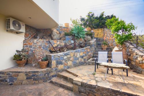 a patio with two chairs and a stone wall at Princess Sissi, Villa-House with private pool and garden in Sissi