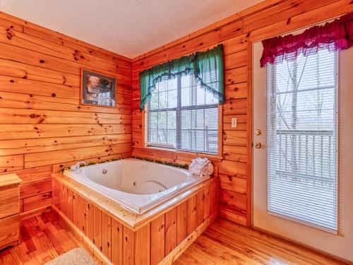 a bath tub in a room with wooden walls and windows at Hawks Point Lodge, 5 Bedrooms, Sleeps 10, Pool Access, Hot Tub, Pool Table in Sevierville