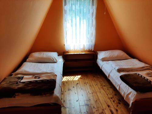 two beds in a room with a window at Domki nad potokiem in Baligród