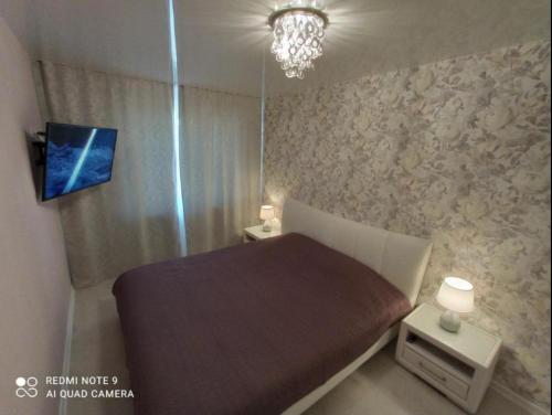 a small bedroom with a bed and a chandelier at Comfortable apartment in center in Narva